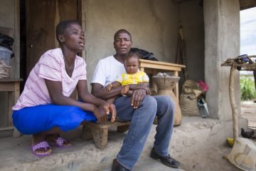 Harrison Sakela, the first Ebola survivor in Liberia, sits outside his home with his wife and young daughter. 