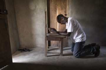 Harrison prays inside his home in Lofa County, Liberia. His house is located a short walk from the Ebola Treatment Unit.