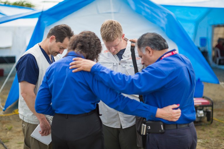 Lance Plyler (left) and Elliott Tenpenny (center) from Samaritan’s Purse pray with chaplains from the Billy Graham Evangelistic Association outside of the emergency field hospital tents in Chone, Ecuador. Plyler and Tenpenny took turns managing the emergency field hospital over the past two months.