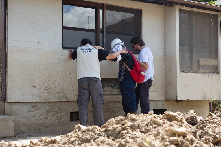 Members of our Disaster Assistance Response Team pray with a worker helping clean up flooded homes in Southern Japan