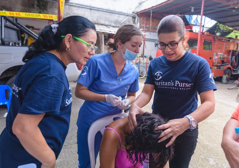 Doctor Maria De Los Angeles Sarmiento (right) and two nurses assess a woman's wounded head.