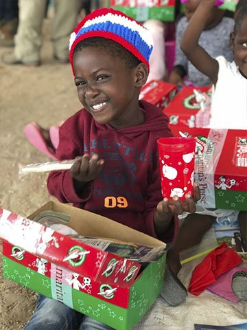 girl smiles at shoebox gift contents