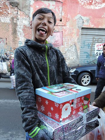 Boy with cheeky grin and shoebox gifts