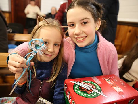 Two girls smile with gifts