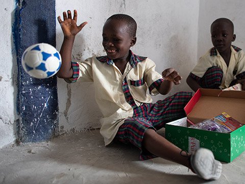 Boy plays with football from shoebox