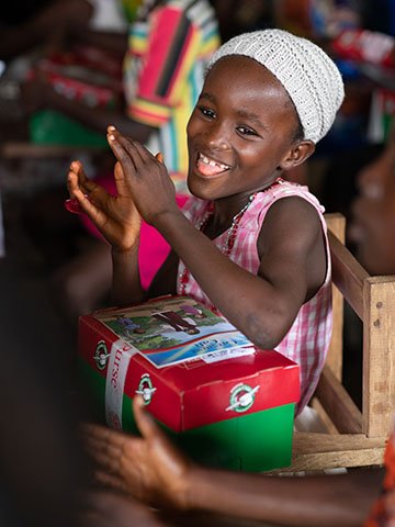 Girl claps and celebrates receiving shoebox gift