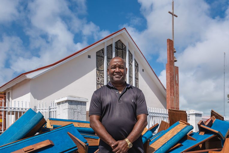 Pastor Keith Russell stands in front of First Baptist Church roughly six months after Hurricane Dorian damaged their pews.