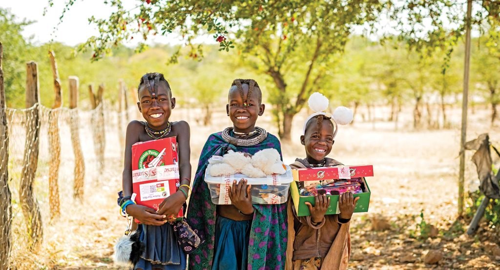 Three children holding their Operation Christmas Child shoebox gifts