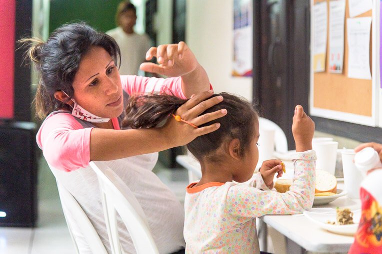 Maria puts her daughter's hair in a ponytail at breakfast at the Samaritan's Purse shelter in Bucaramanga.
