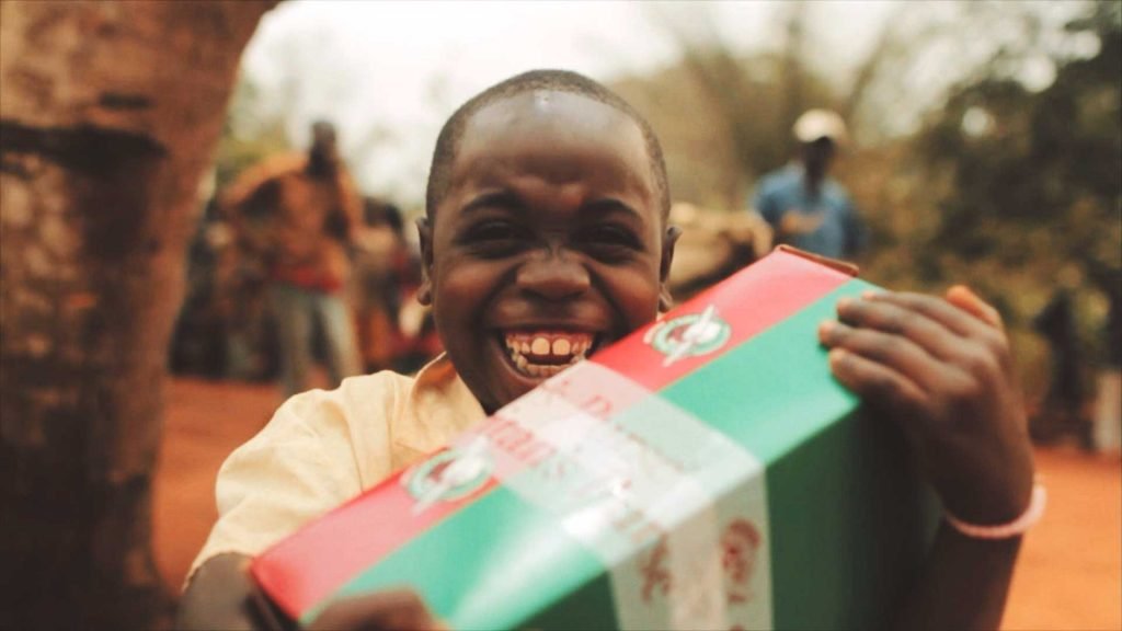 Boy grins with shoebox