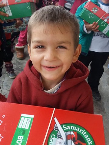Young boy smiles with shoebox gift