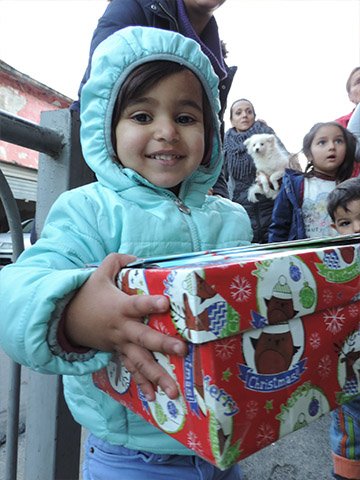 Girl smiles with red wrapped shoebox gift