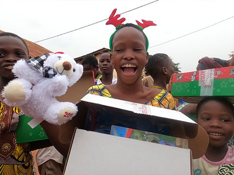 child smiles with cuddly toy and reindeer antlers