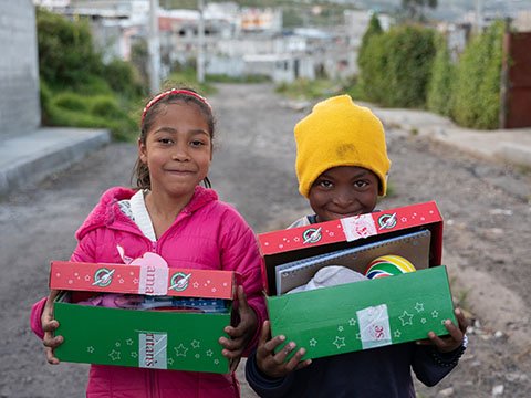 boy and girl smile holding shoebox gifts