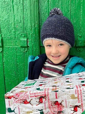 boy smiles with wrapped shoebox gift