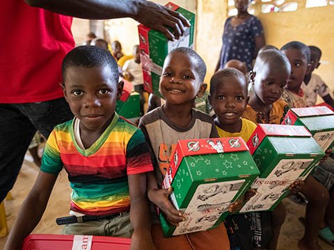 young boys smile with shoebox gifts