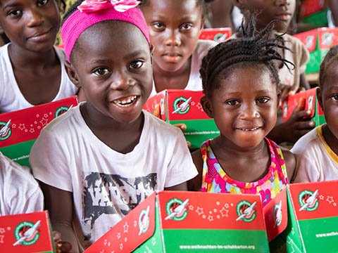 Two girls smile with shoebox gifts