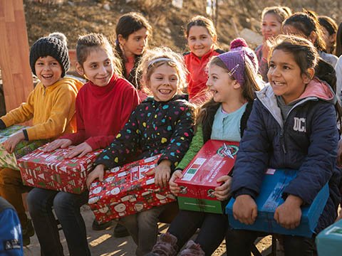 group of children sitting with shoebox gifts