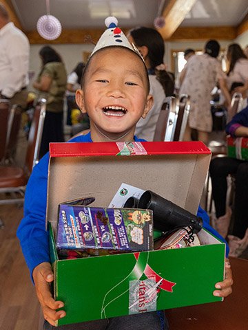 boy with party hat smiles with shoebox