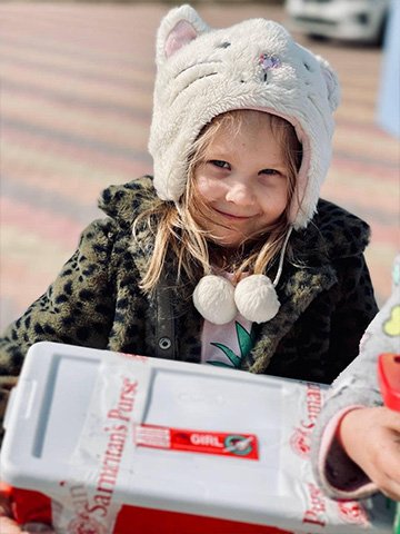 girl with cat hat smiles with shoebox