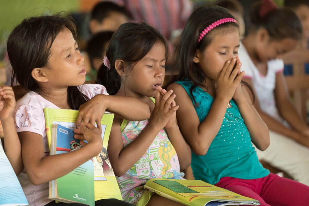 Closing their eyes to pray, young children in Peru are taught the significance of communication with God through The Greatest Journey program.